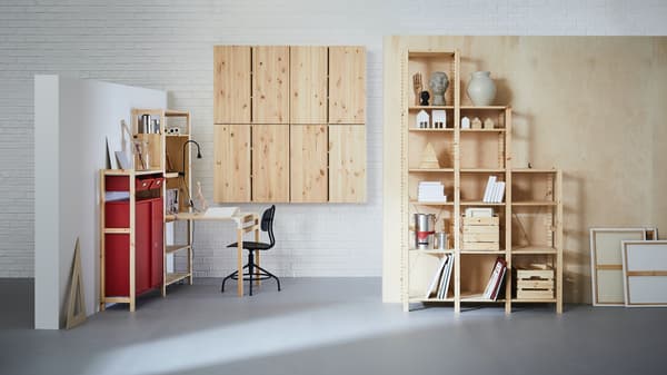 Set de muebles IVAR en un espacio de muros blancos y piso gris claro. Se ven estantes escalonados, muebles a muro con puertas y un escritorio plegable, todos de color madera de pino natural. 
