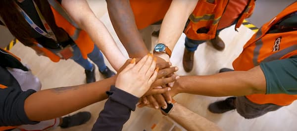 Several people around a circle with their hands extended on top of one another's.