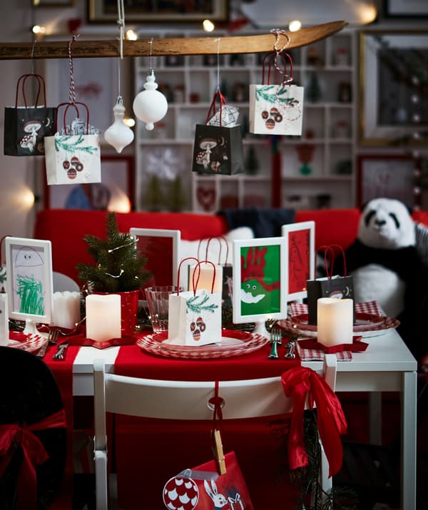 Several two-sided IKEA TOLSBY frames containing holiday art, set on a desk.