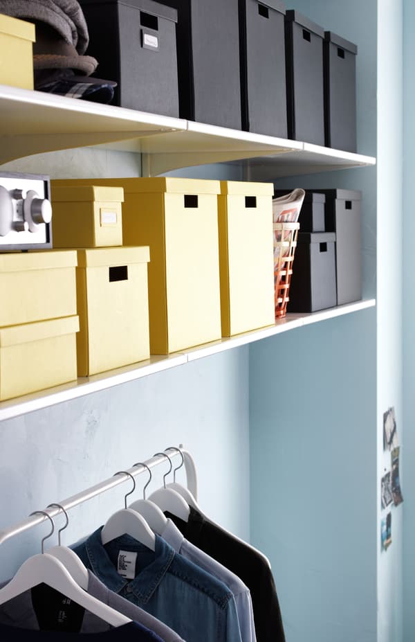 Shelves on brackets above an IKEA clothes stand. Storage boxes on the shelves.