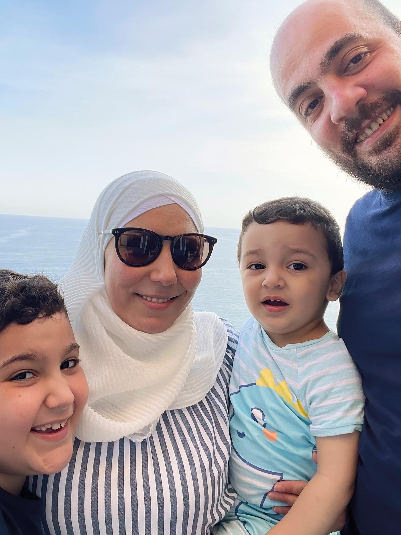 シリア難民でイケアコワーカーのTarekが、妻と子ども2人と一緒にいる。後ろには海。