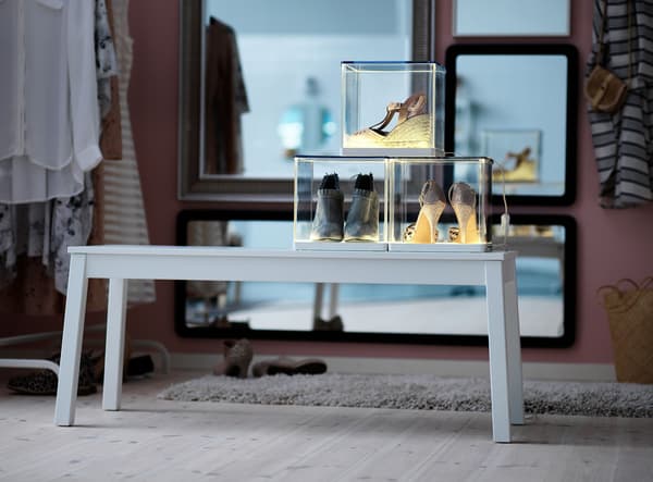 Shoes on display in SYNAS light boxes on top of a light grey bench.