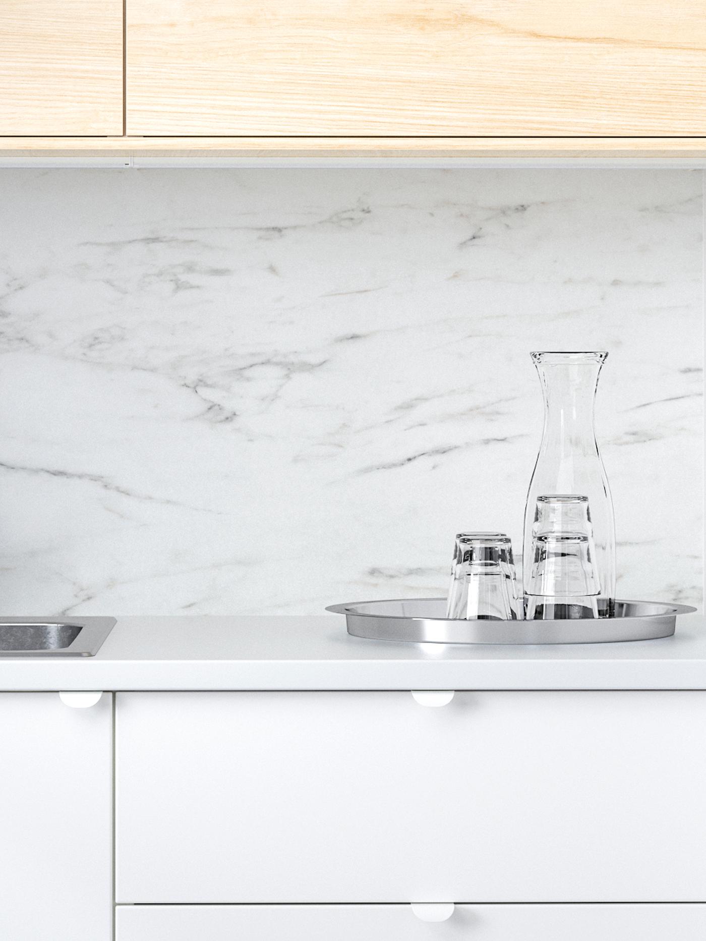 SIBBARP wall panel in white marble effect in a kitchen with fronts in white and birch, a tray with glasses and a carafe.