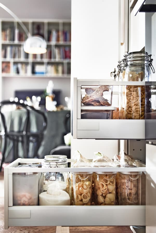  Side view of open kitchen drawers, filled with glass containers holding food.