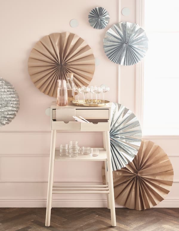 Silver and brown rosettes of different sizes on a wall, behind a small work desk carrying glasses and drinks.