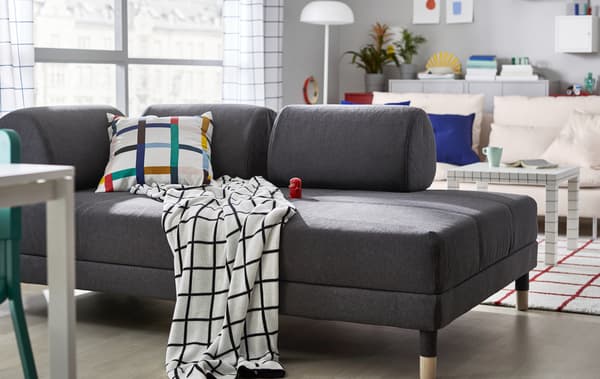 Siva sofa u dnevnoj sobi s tekstilima s grafičkim šarama.