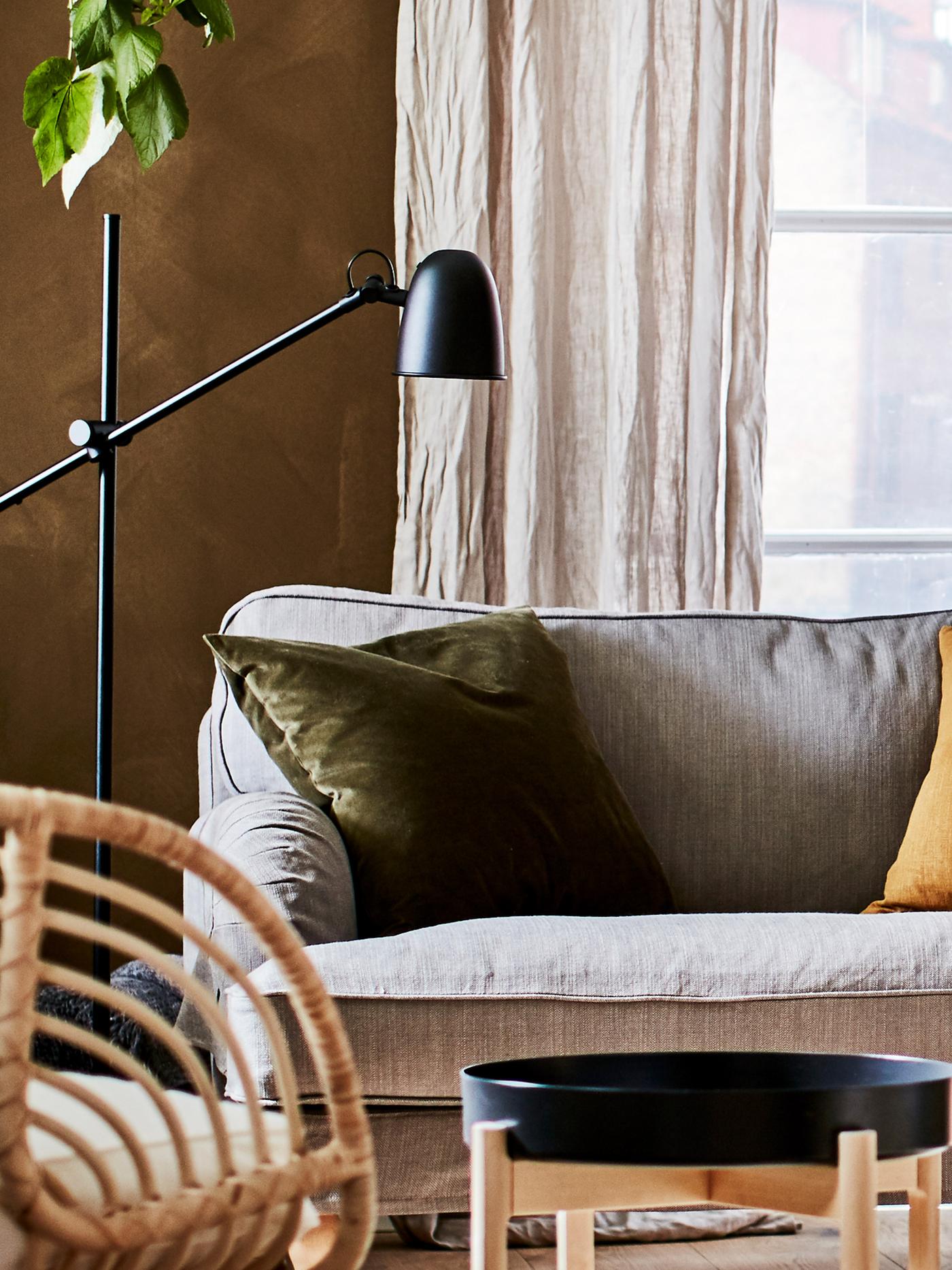 SKURUP lamp directed on a STOCKSUND sofa. A bamboo chair and a side table in front of the sofa.