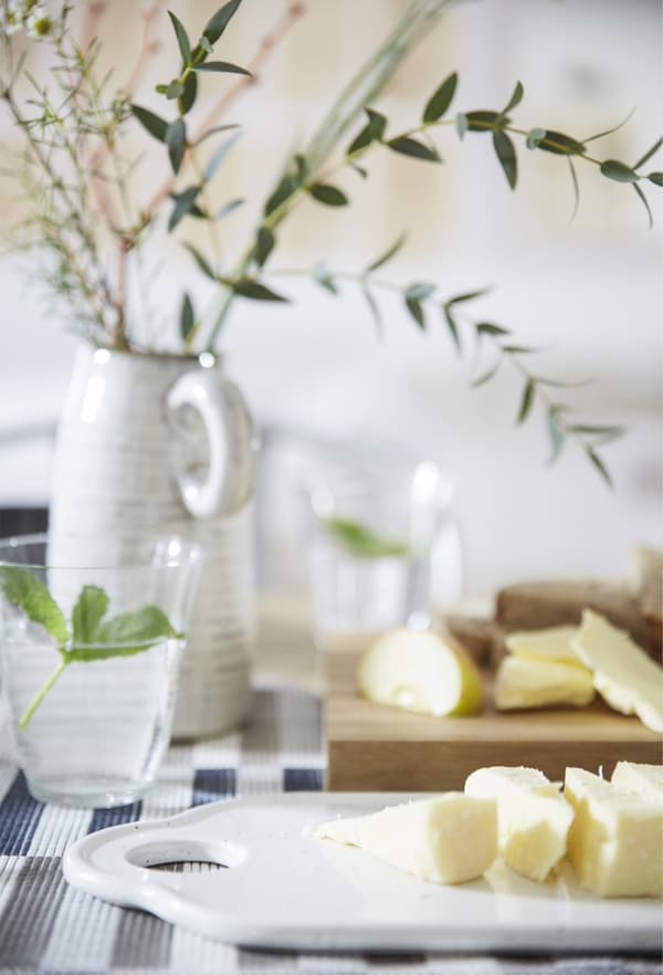 Sliced food on chopping boards, a glass of water and a simple centrepiece in a vase.