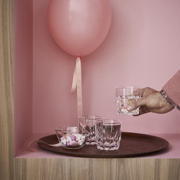 SMAKKÄNSLA glasses and a VÄLFYLLD glass bowl on a brown TILLPLATTAD tray with a pink balloon.