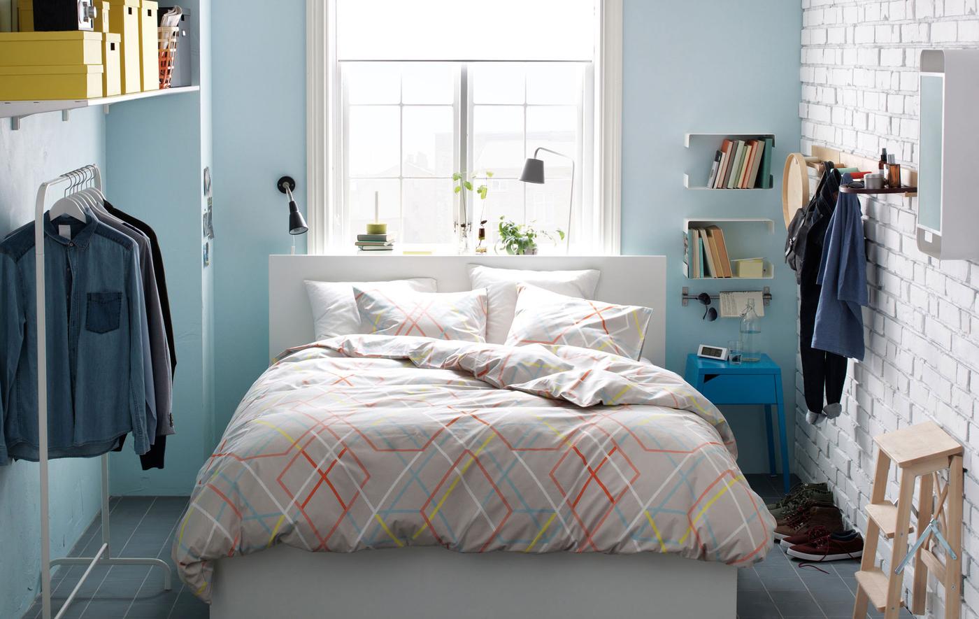 Small bedroom with IKEA double bed, clothes stand, shelves, hooks, mirror, lamps and stepstool.
