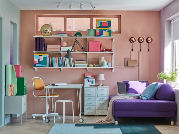 Small home office, with a LINNMON/KRILLE table in white with legs on castors, some shelves, storage cabinets and a sofa bed.