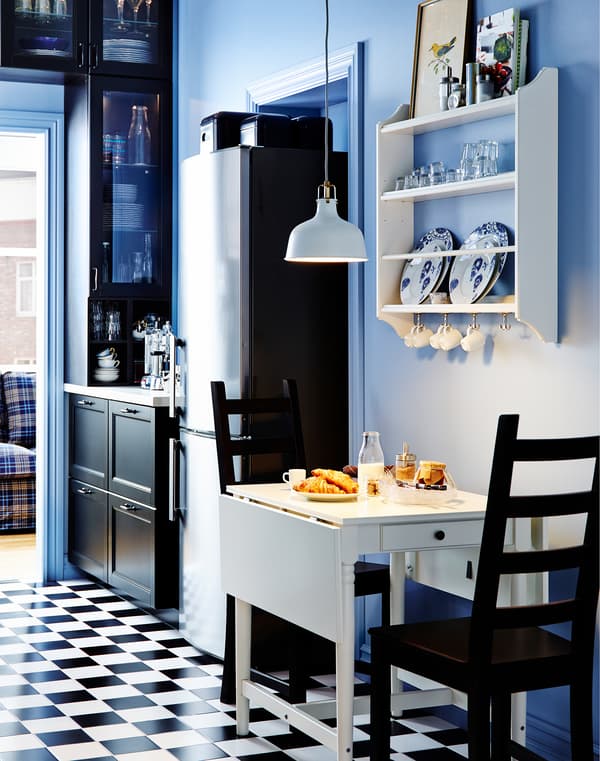 Small IKEA drop-leaf table and two chairs. Plate storage rack on the wall above.