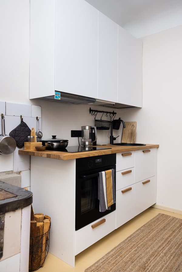 Small kitchen with closed cabinets and an open wall shelf for additional storage.