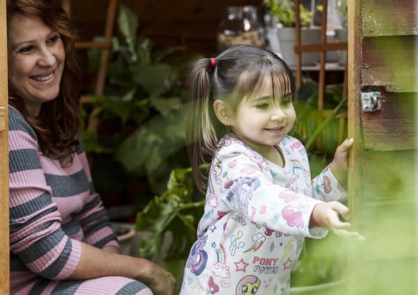 Smiling woman looking at child playing.  