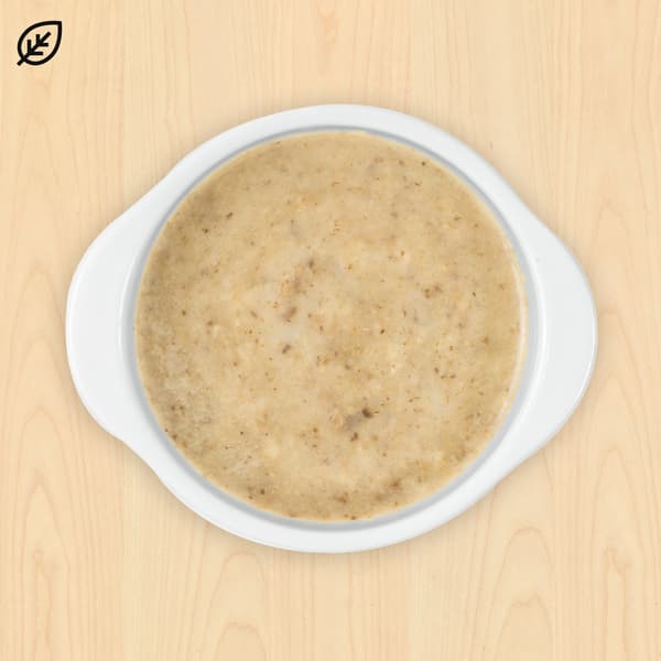 Smooth beige flatbread with visible grains on a white ceramic plate, set against a light wooden background. A leaf icon is in the top left corner.