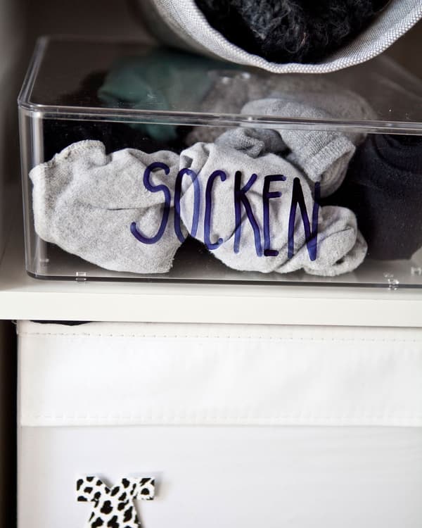 Socks in a labelled box on a white shelf.