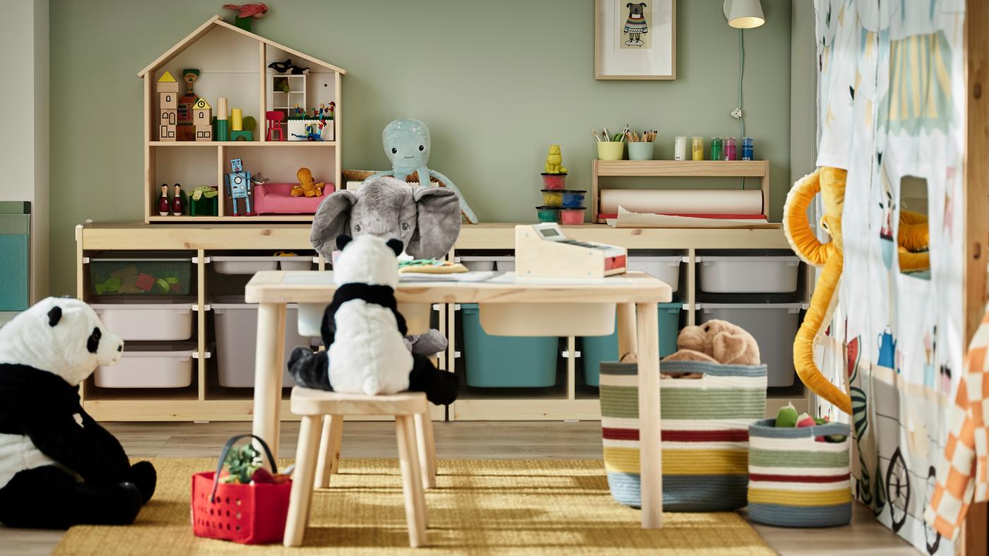 Soft toys around a pine children’s table with stools, plus two storage combinations with pine frames holding various toys.