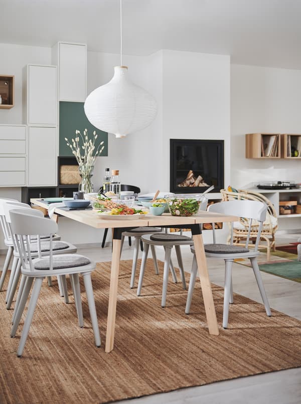 Soggiorno e zona pranzo in un unico grande ambiente, con caminetto, combinazione di mobili da parete e tavolo YPPERLIG con sedie OMTÄNKSAM.