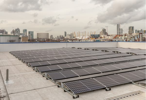 Solaranlage auf einem Gebäudedach. Im Hintergrund ist eine Skyline erkennbar.