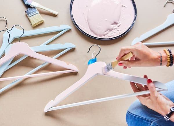 Someone painting a white BUMERANG hanger pink.