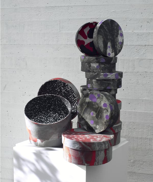 Stacks of patterned grey, purple and red boxes from the IKEA ANNANSTANS collection in different sizes with lids.