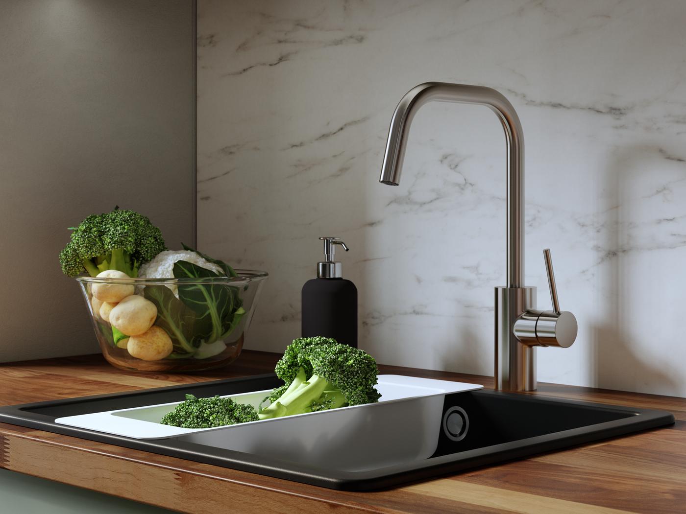 Stainless steel VIMMERN kitchen mixer tap with handspray on a round BOHOLMEN inset sink, green leaves on the edge.