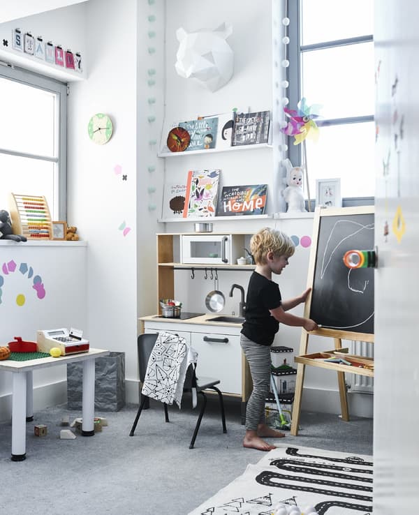 Stanley, a small boy, playing in his bedroom as he draws with chalk on his easel.