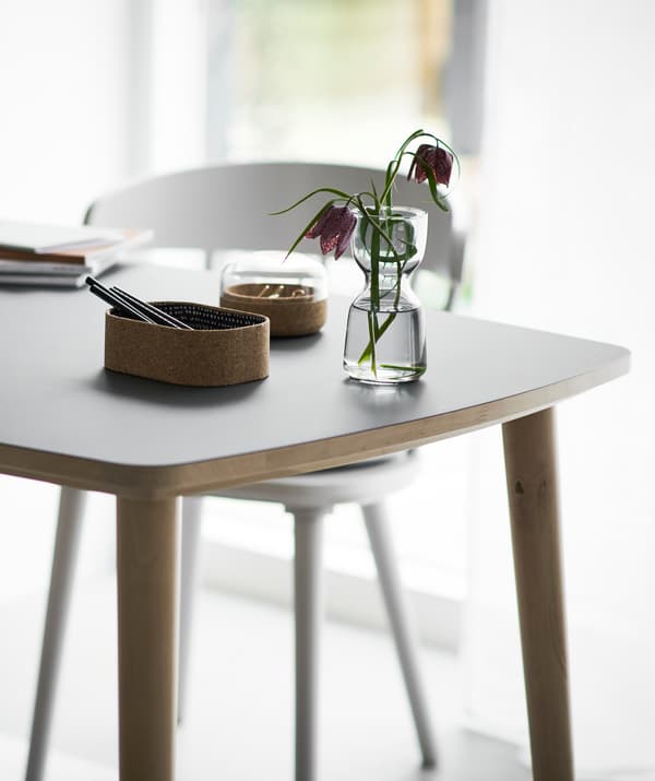 Stationery and a vase of flowers on a table with a white chair.