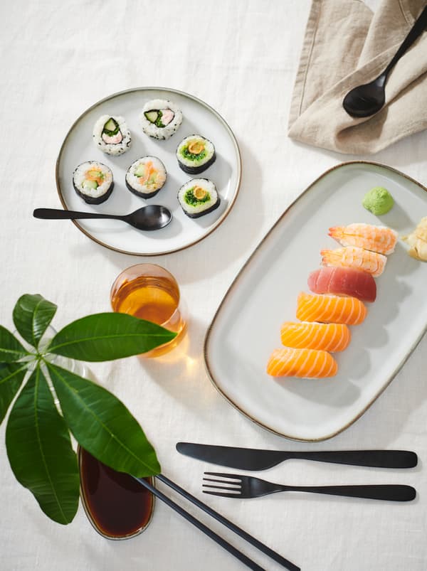 Stůl s bílým ubrusem, sushi na talířcích různého tvaru