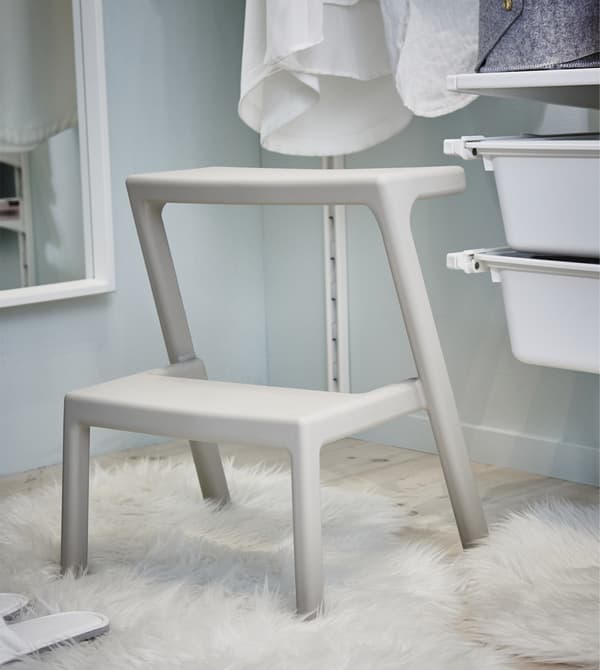 Sturdy and lightweight MÄSTERBY beige step stool inside the walk-in closet.