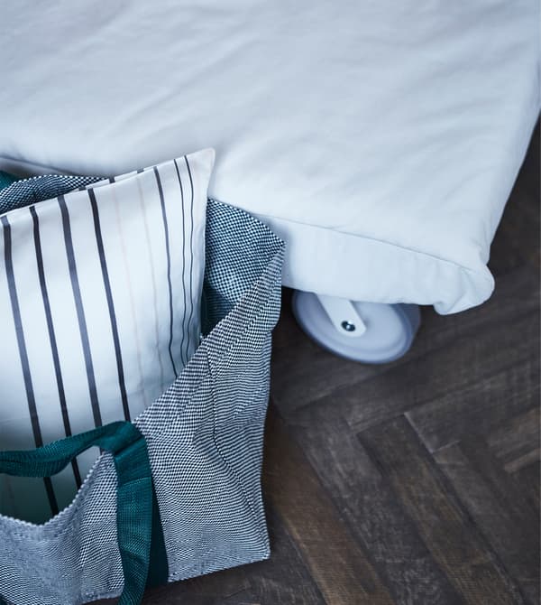 Sturdy but stylish polypropelene bags like the IKEA YPPERLIG can hold bedding for guests. It comes in a white mesh pattern with green or burgundy nylon straps for a modern look.
