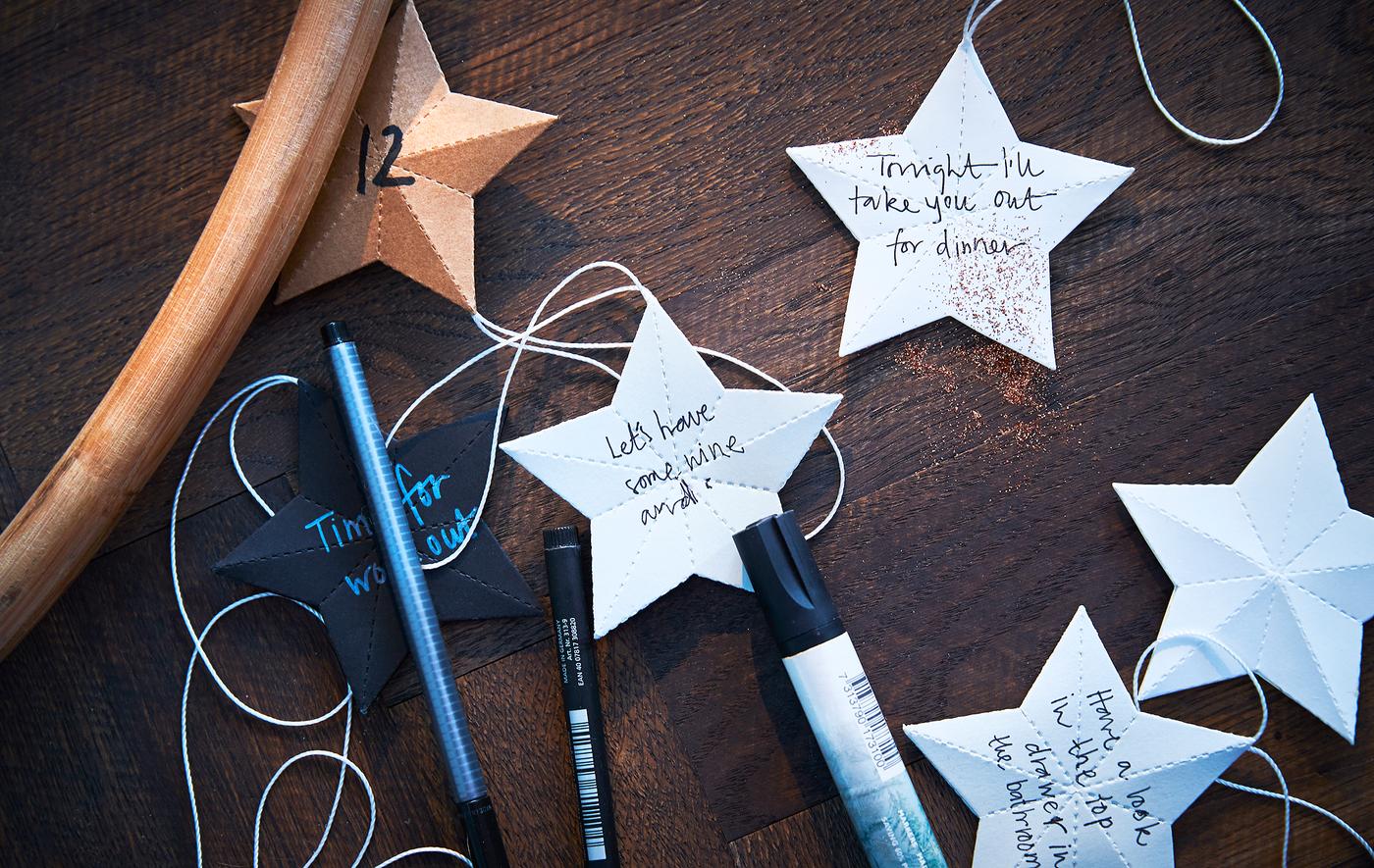 Stylos et étoiles en papier avec messages écrits, posés sur une table.