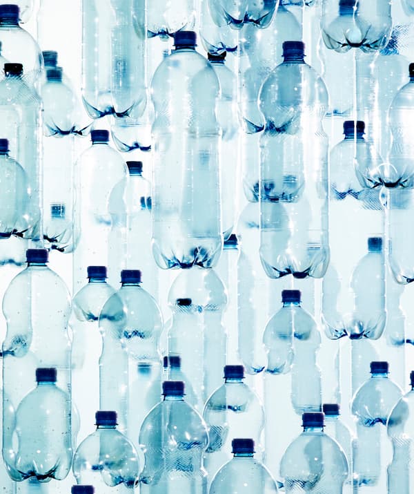 Superposition de multiples bouteilles en plastique transparent à capsule bleue.