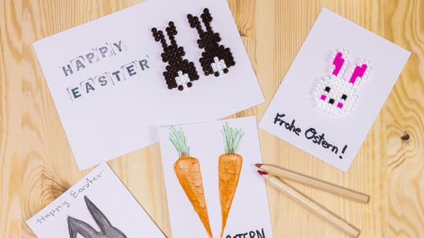 Sur une table sont posés des petits papiers blancs sur lesquels sont dessinées des décorations de Pâques.