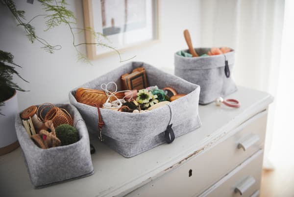 Sur une vieille commode usée sont posés des paniers RAGGISAR en tissu remplis de babioles et de menus objets.