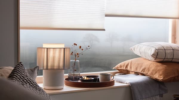 SYMFONISK lamp with WiFi speaker alongside various ornaments and magazines.