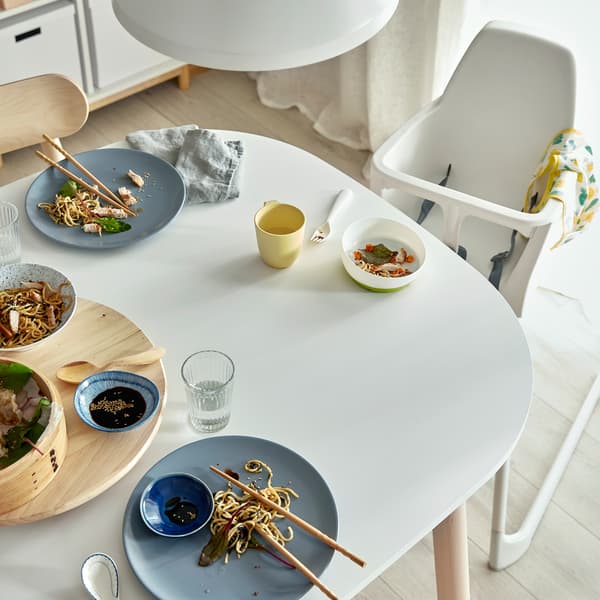Table blanche après un repas en famille. Une chaise haute est disposée près de la table.