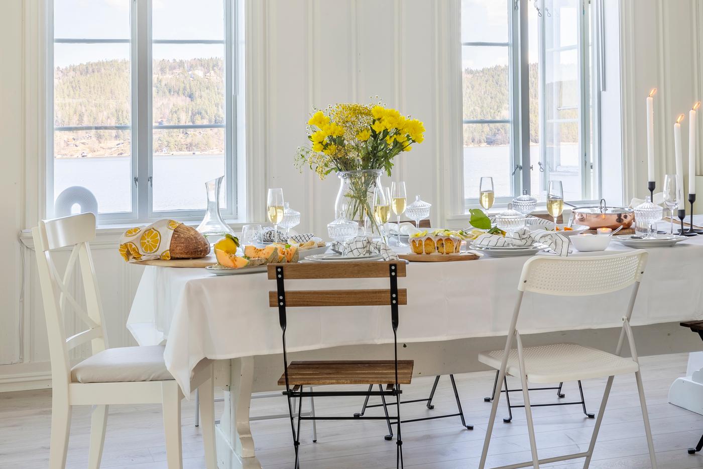 Table de salle à manger élégante dressée en blanc avec des assiettes de pâtes, des verres à vin et un citron frais en guise de décoration de table.