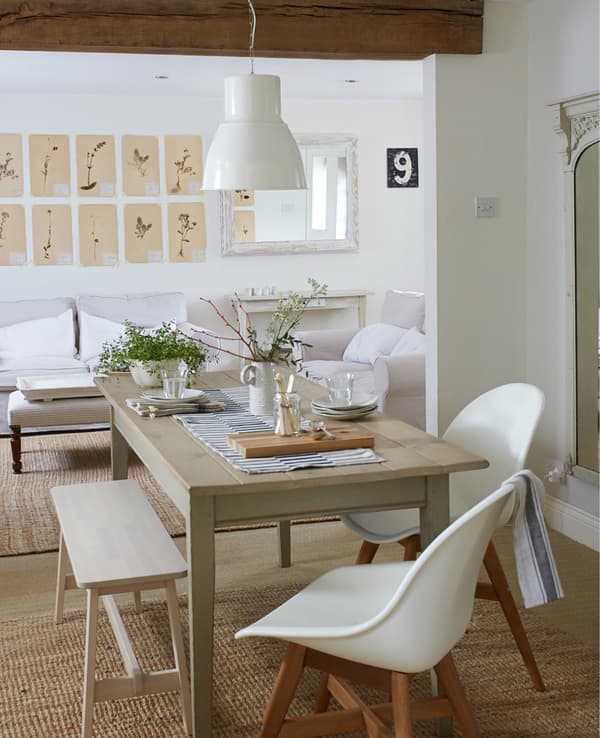 Table de salle à manger installée dans un salon décloisonné avec poutres en bois apparentes.