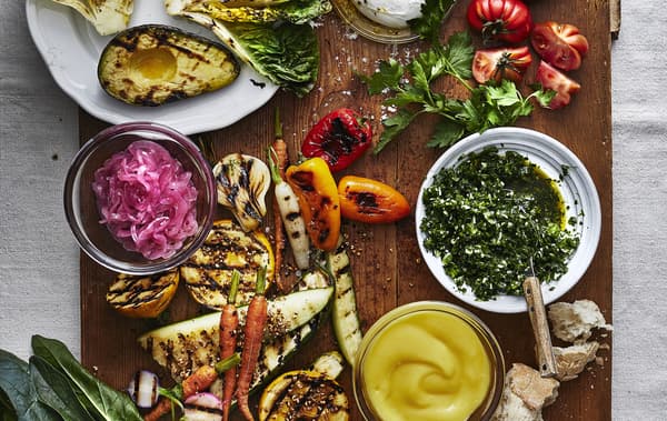Table garnie de légumes grillés et d’herbes.