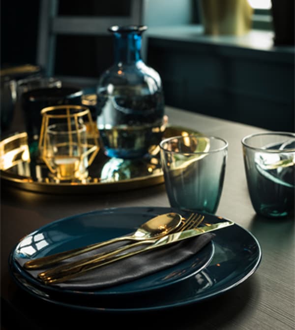 Tableware in shades of deep green are set with gold-colored flatware.