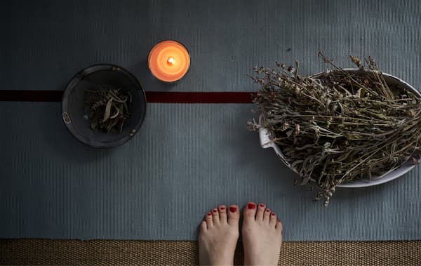 Tapis de yoga, bougie et bols d’herbes.
