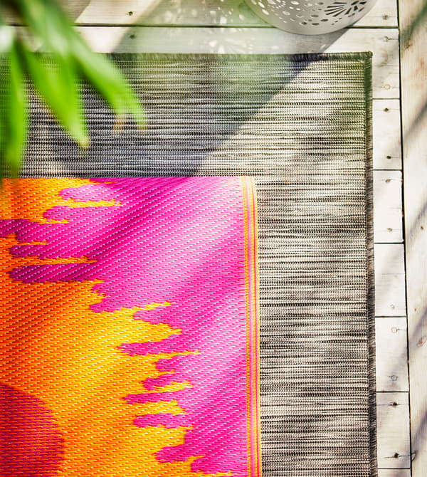 Tapis orange et rose posé sur un autre, blanc et noir.