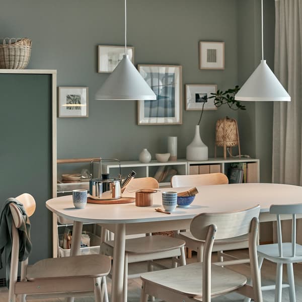 Tavolo da pranzo con servizio da tè per due persone con sopra due lampade a sospensione NÄVLINGE accese, che diffondono una luce soffusa e accogliente - IKEA