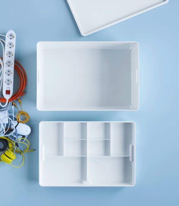 Tech accessories and chargers waiting to be put away in a white IKEA KUGGIS box with two levels.