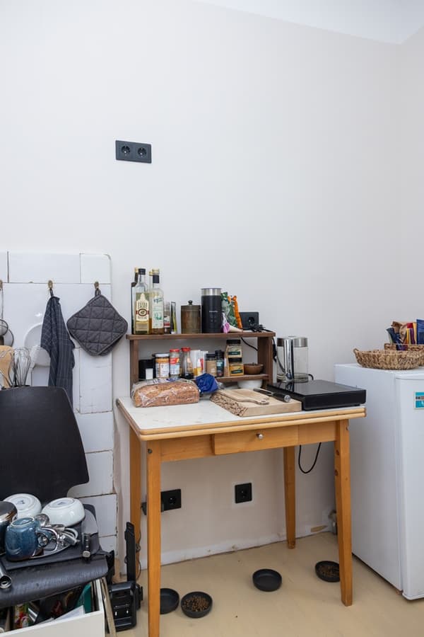 Temporary kitchen area with a small table, appliances and dishes in a compact room.