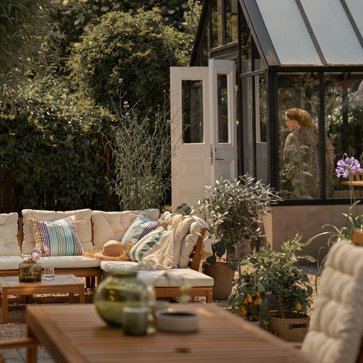 Terrasse mit einem hellbraunen Modulsofa mit beigen Polstern, einem hellbraunen Tisch und einem Hochlehner.