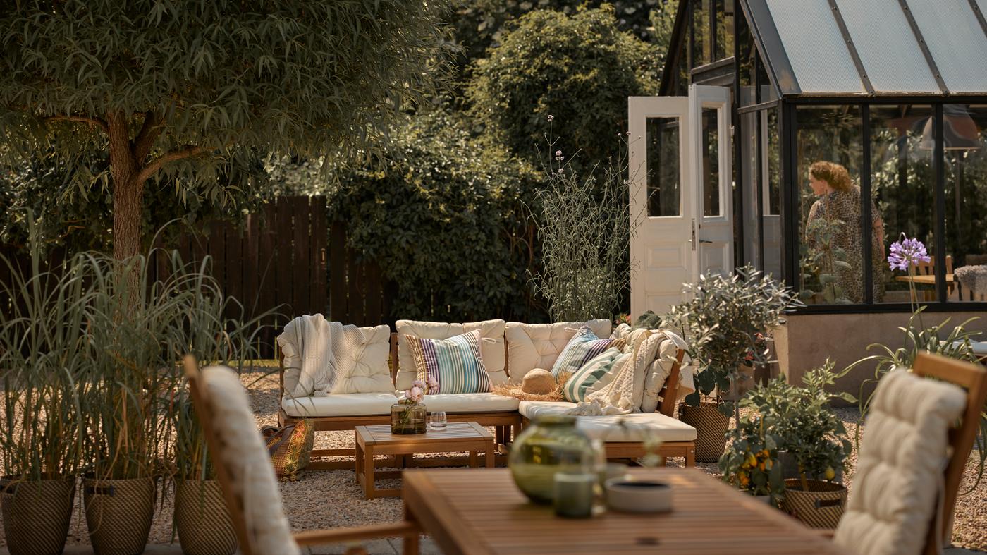 Terrasse mit hellbraunem Modulsofa mit beigefarbenen Kissen, einem hellbraunen Outdoor-Tisch und einem Hochlehner.