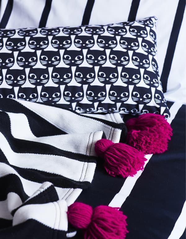 Textiles monochromes ornés de pompons roses.
