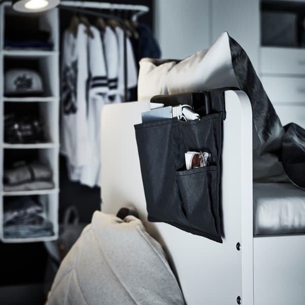 The backside of a bed's headboard where a black bed pocket hang and store books and more.